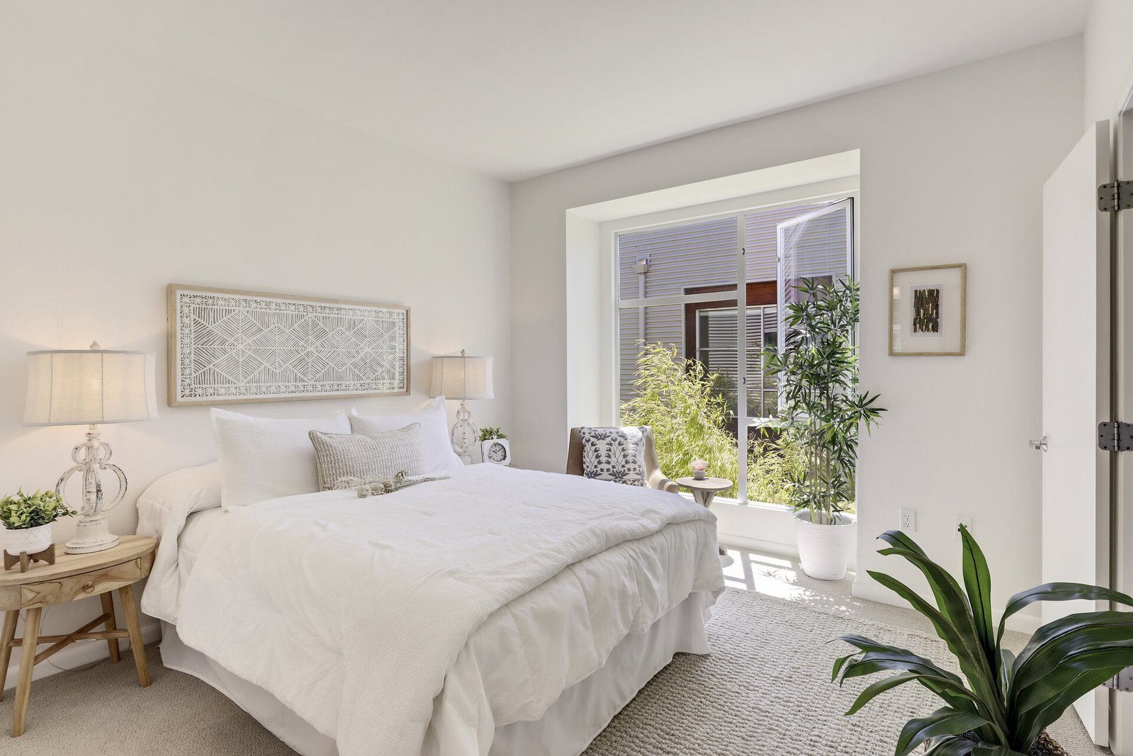 Bright bedroom with white walls and large window. 