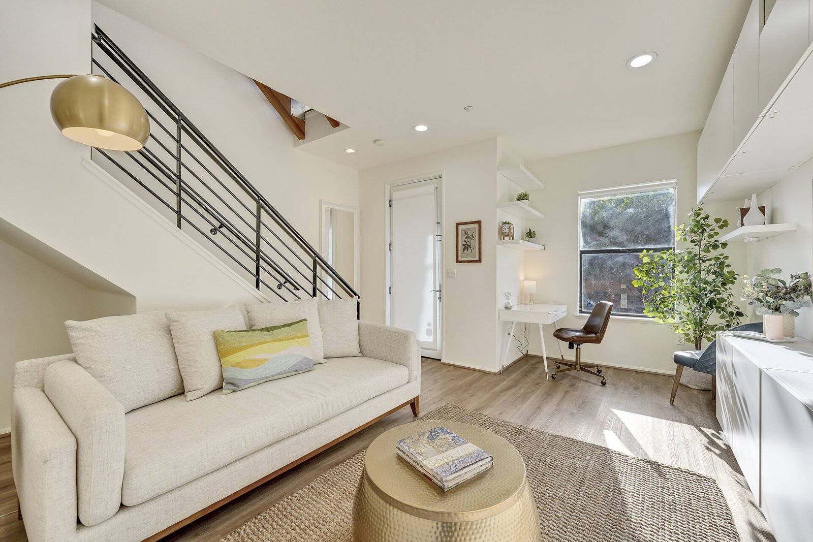 Entry/office area with a white desk, a leather office chair, and a view of a staircase with black railings.